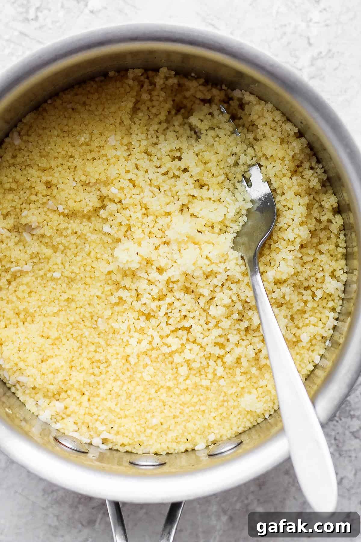 Steamed couscous being fluffed with a fork.