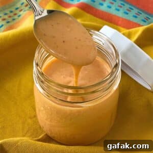 Spoon lifting homemade bang bang sauce from a small mason jar.