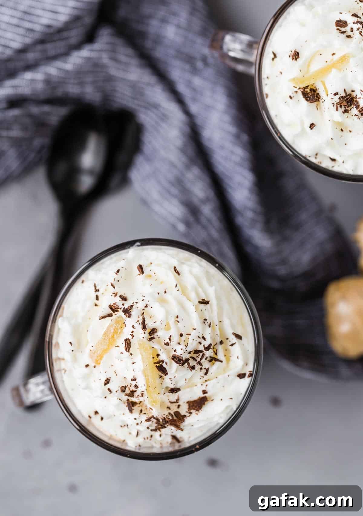 Overhead view of whipped cream in mugs. Spoons also visible.