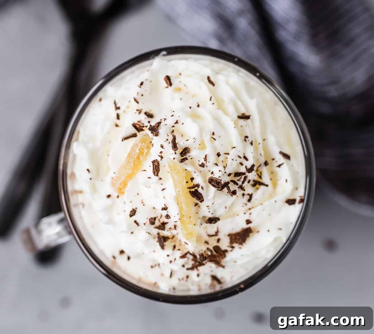 Overhead view of whipped cream topped cocoa, garnished with chocolate shavings and candied ginger.