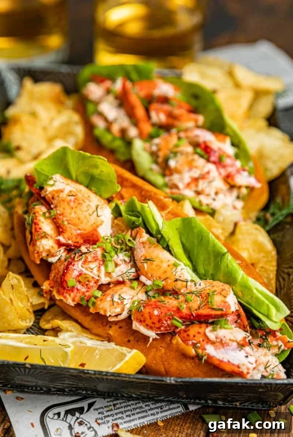 New England Lobster Rolls on a silver plate with potato chips and soda.