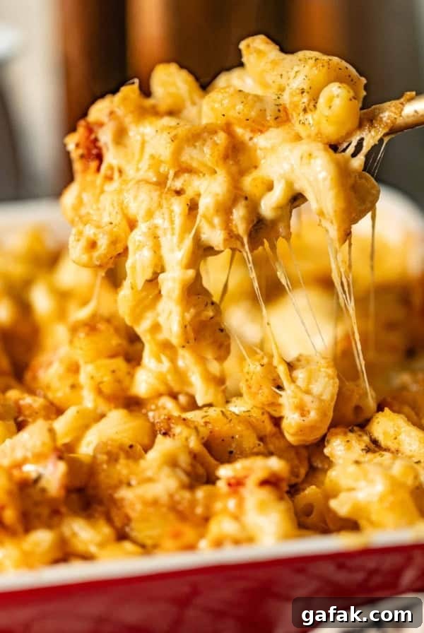 lobster mac and cheese in a casserole dish being scooped out onto a spoon so that you can see the cheese pull
