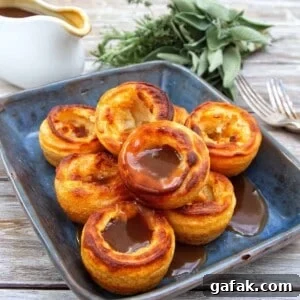 Yorkshire puddings towered on a blue/black plate covered in gravy.