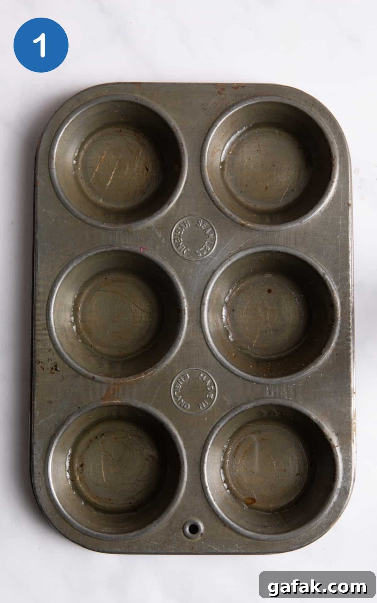 Muffin tray tray with sunflower oil each hole laid on white background.
