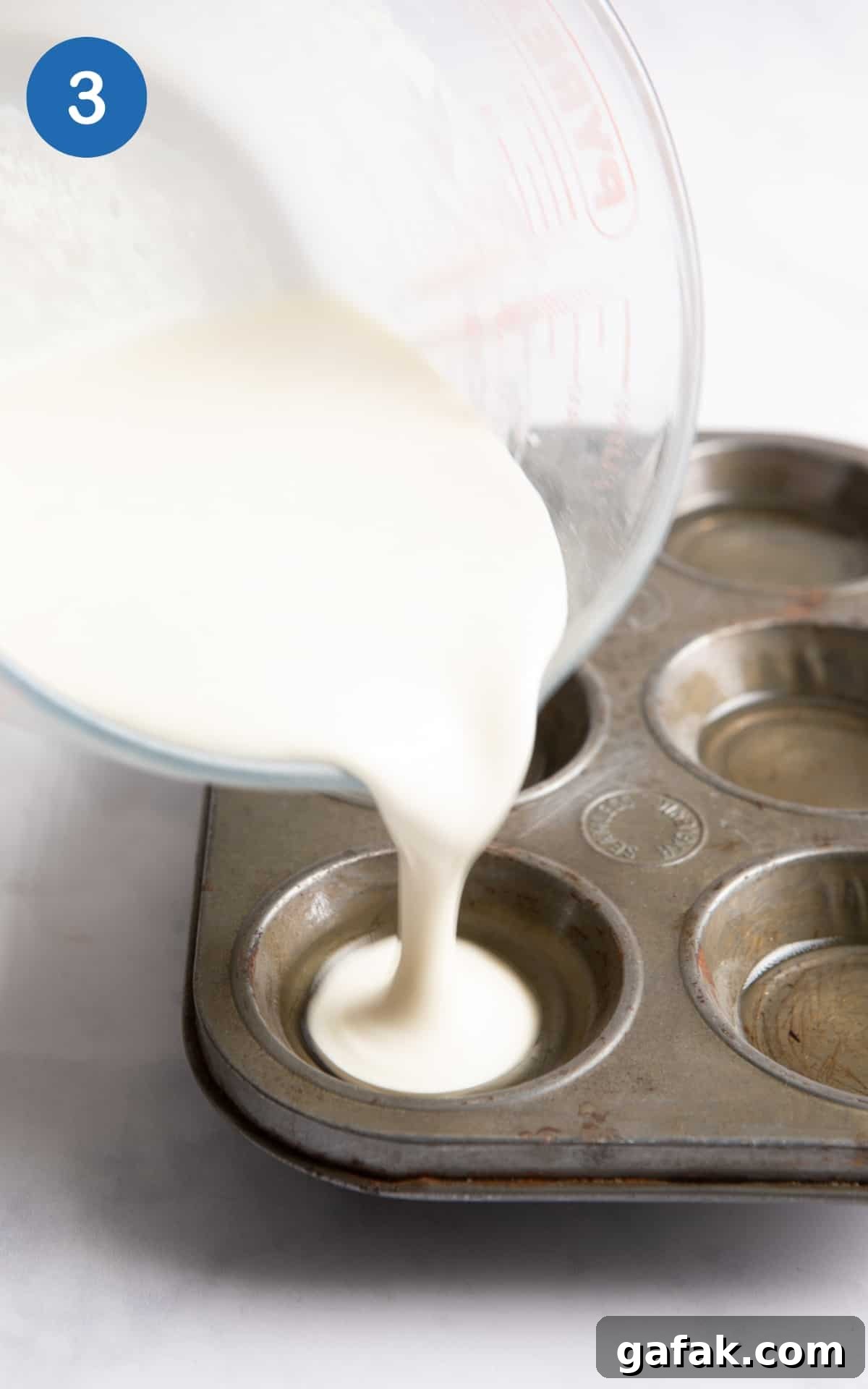 batter being poured into muffin baking tray.
