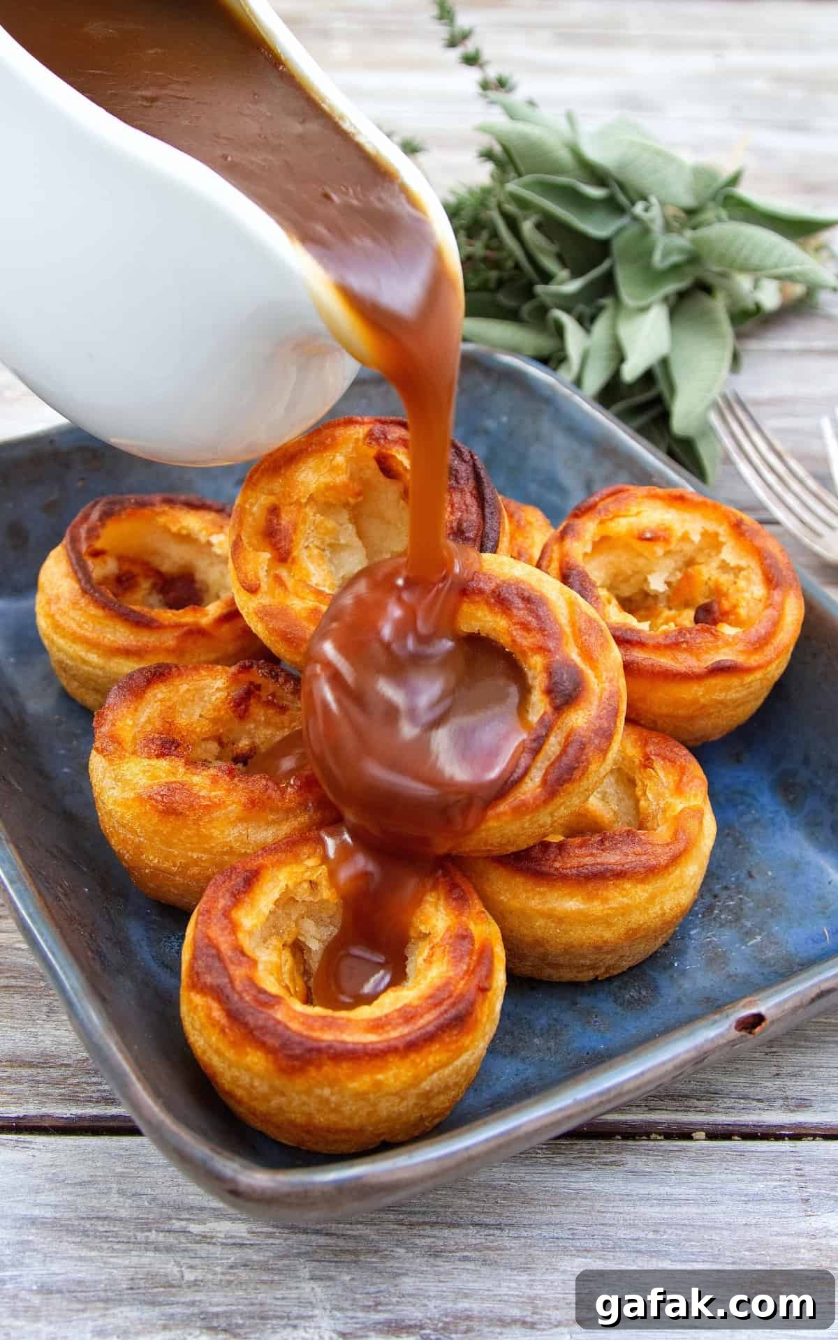 Gravy being poured over a tower of Yorkshire puddings.