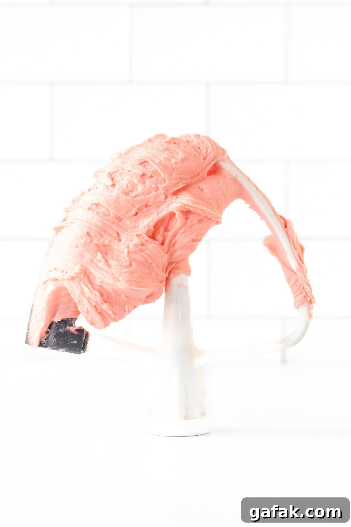 Stand mixer beater covered with pink sugar cookie frosting