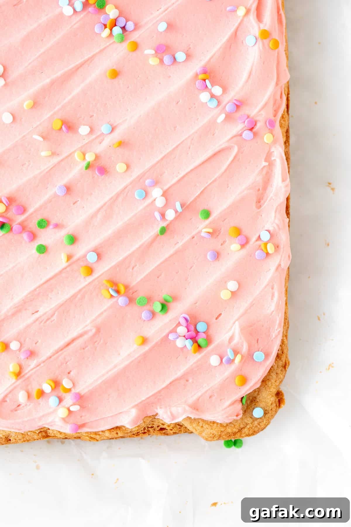 pan of sugar cookie bars topped with pink frosting and sprinkles