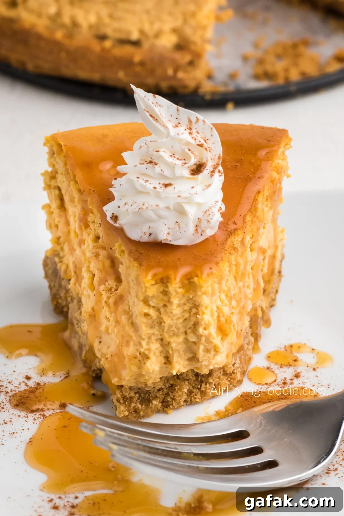 Slice of air fryer pumpkin cheesecake on a plate with a bite missing. 