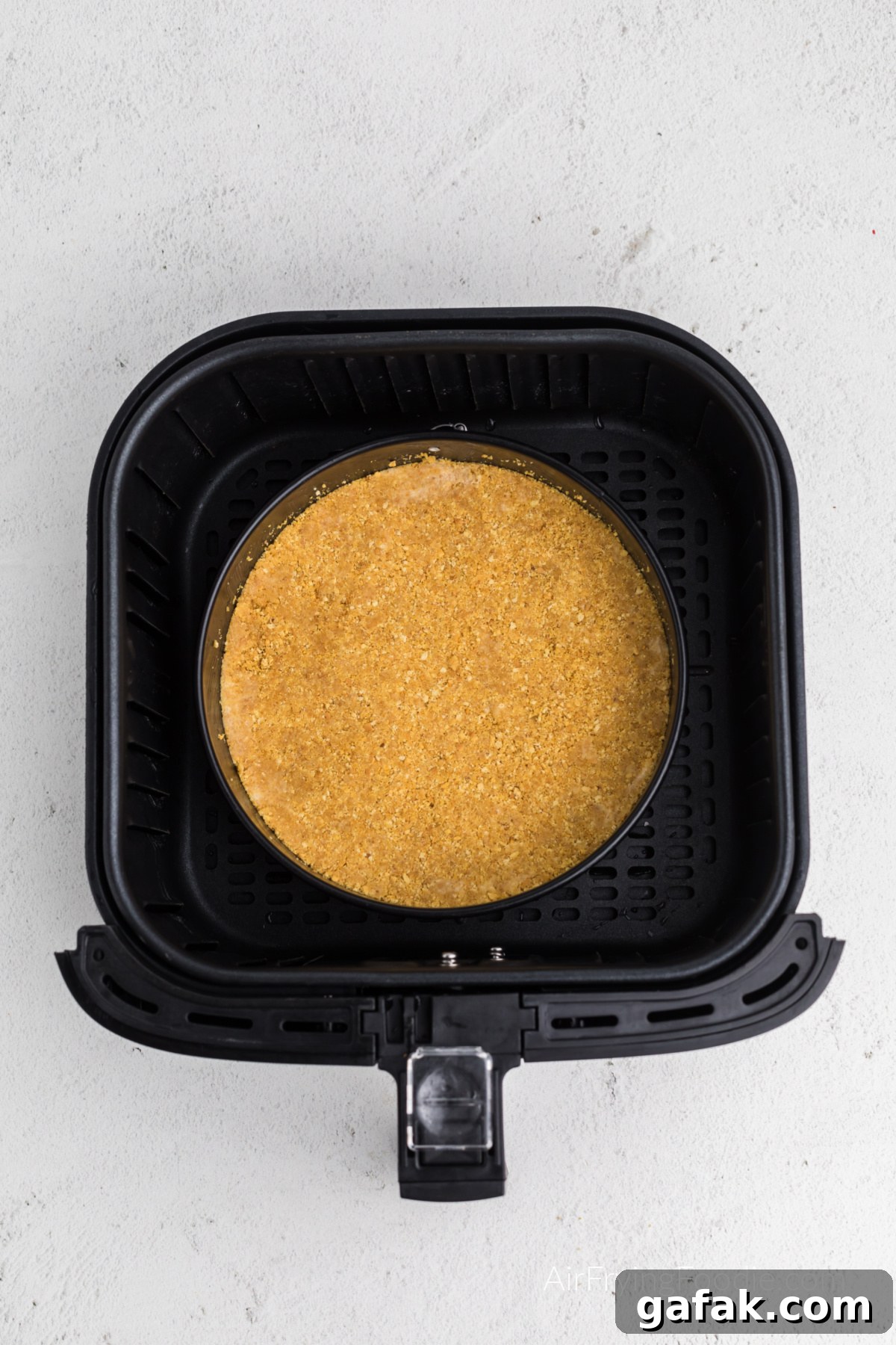 graham cracker crust in the air fryer basket ready to cook