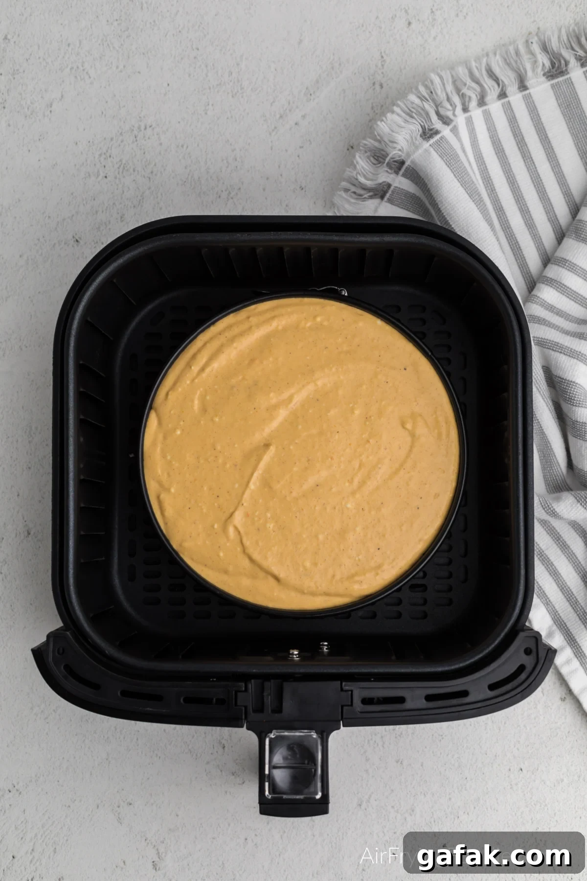 Pumpkin cheesecake in the air fryer basket, ready to be cooked. 