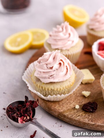 Cupcakes with pink buttercream frosting on top and lemon slice nearby.