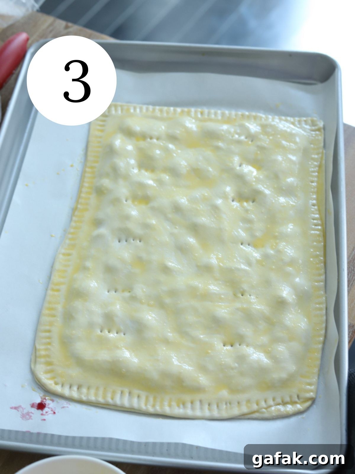 A giant pop tart brushed with egg wash on a baking sheet. 