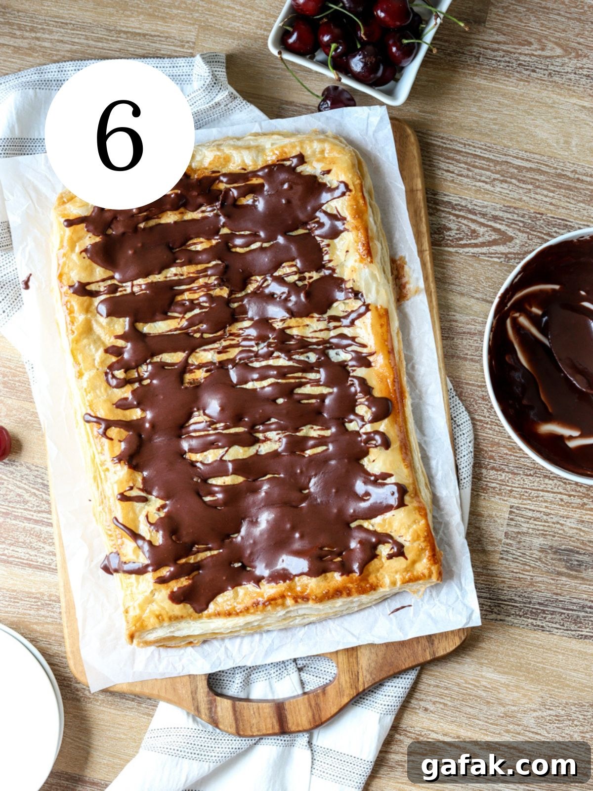 A giant pop tart with chocolate drizzled on top and a bowl of cherries. 
