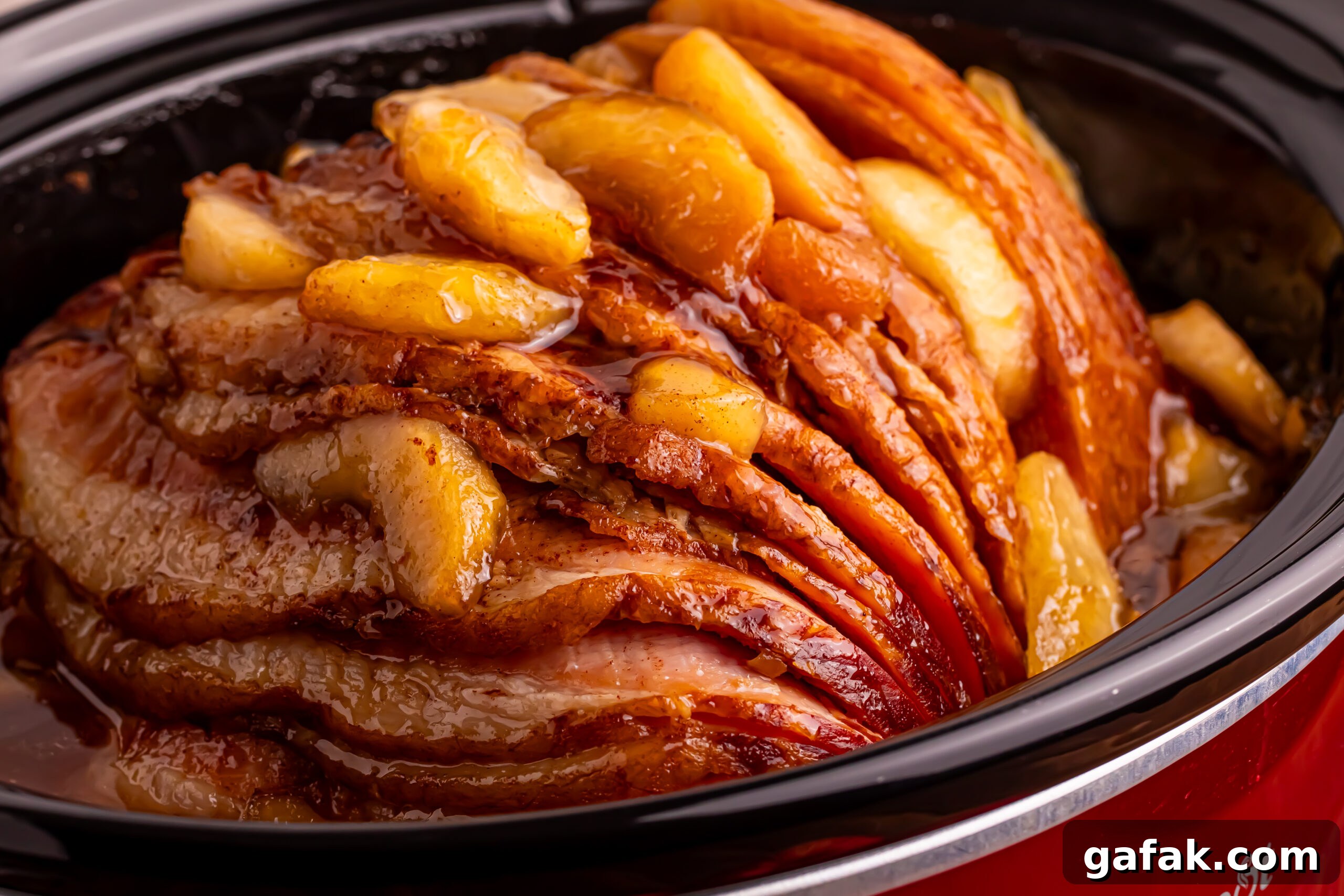 Side view of the Slow Cooker Apple Glazed Ham in a red slow cooker 