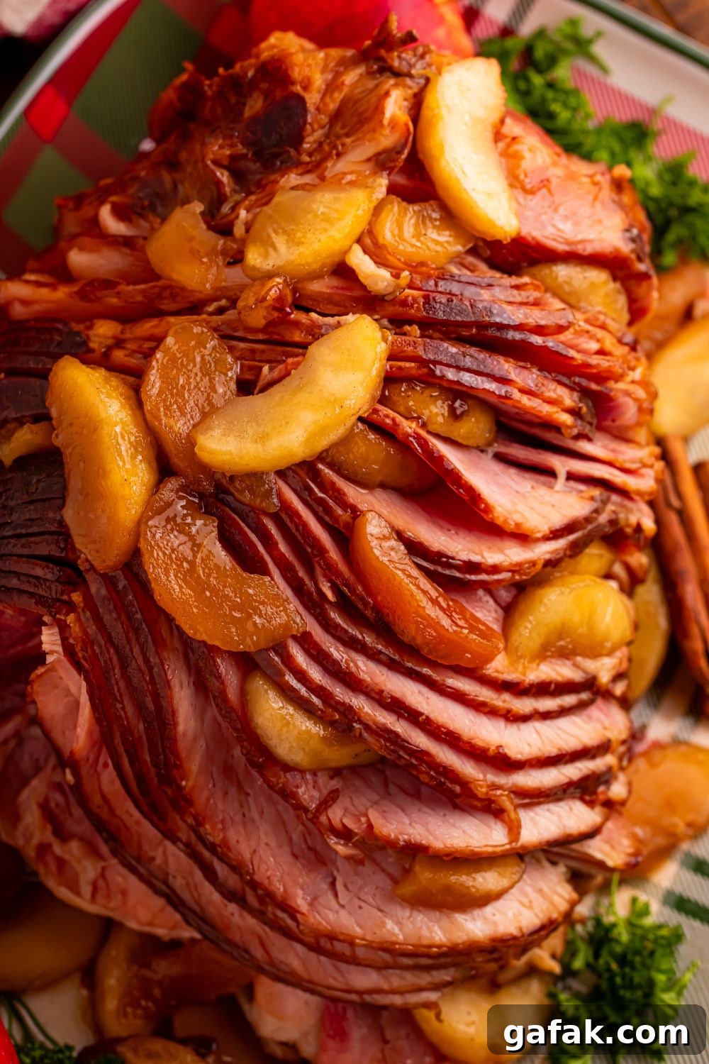 fully cooked Slow Cooker Apple Glazed Ham on a platter garnished with greens and cinnamon apples on top of ham 