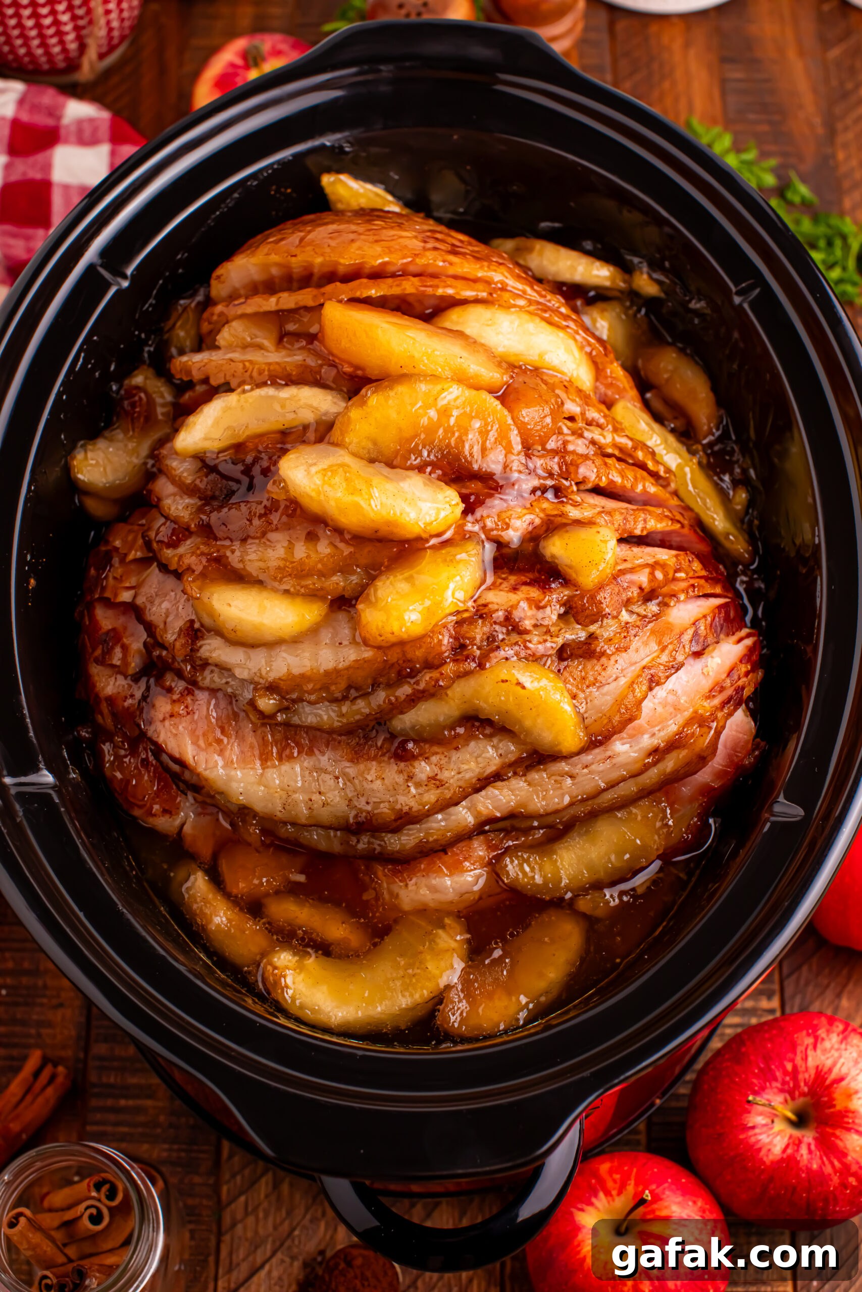 overhead shot of the cooked Slow Cooker Apple Glazed Ham in a black crock pot on a dark wood table 