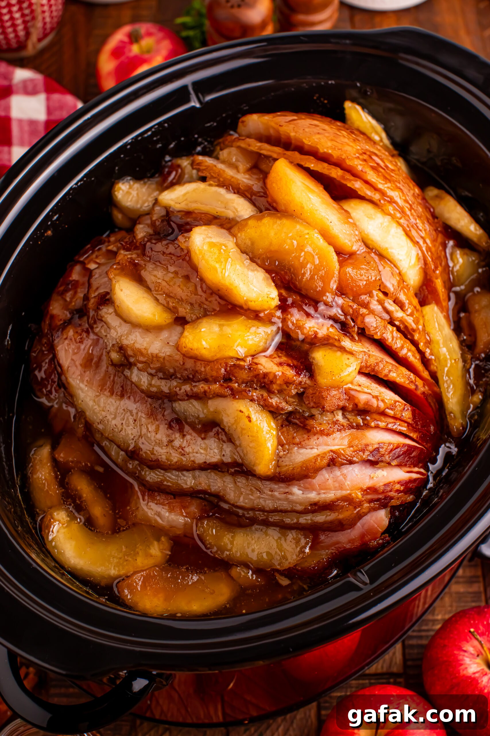 Slow Cooker Apple Glazed Ham in a black crock pot on a dark wood table 