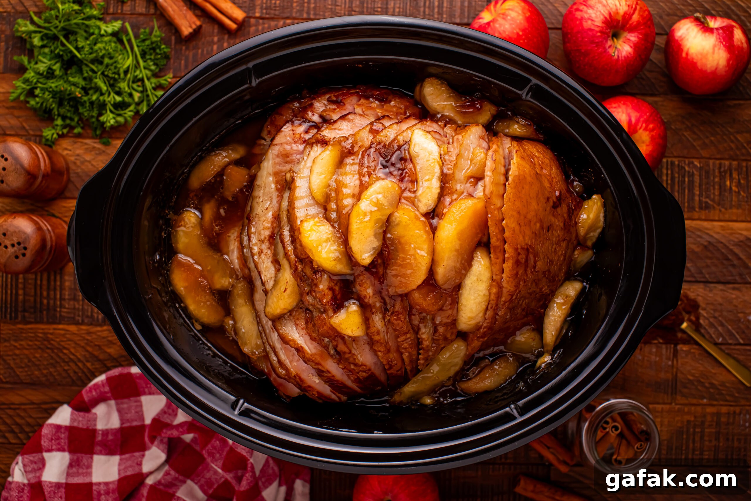 Slow Cooker Apple Glazed Ham in a black crock pot on a dark wood table 