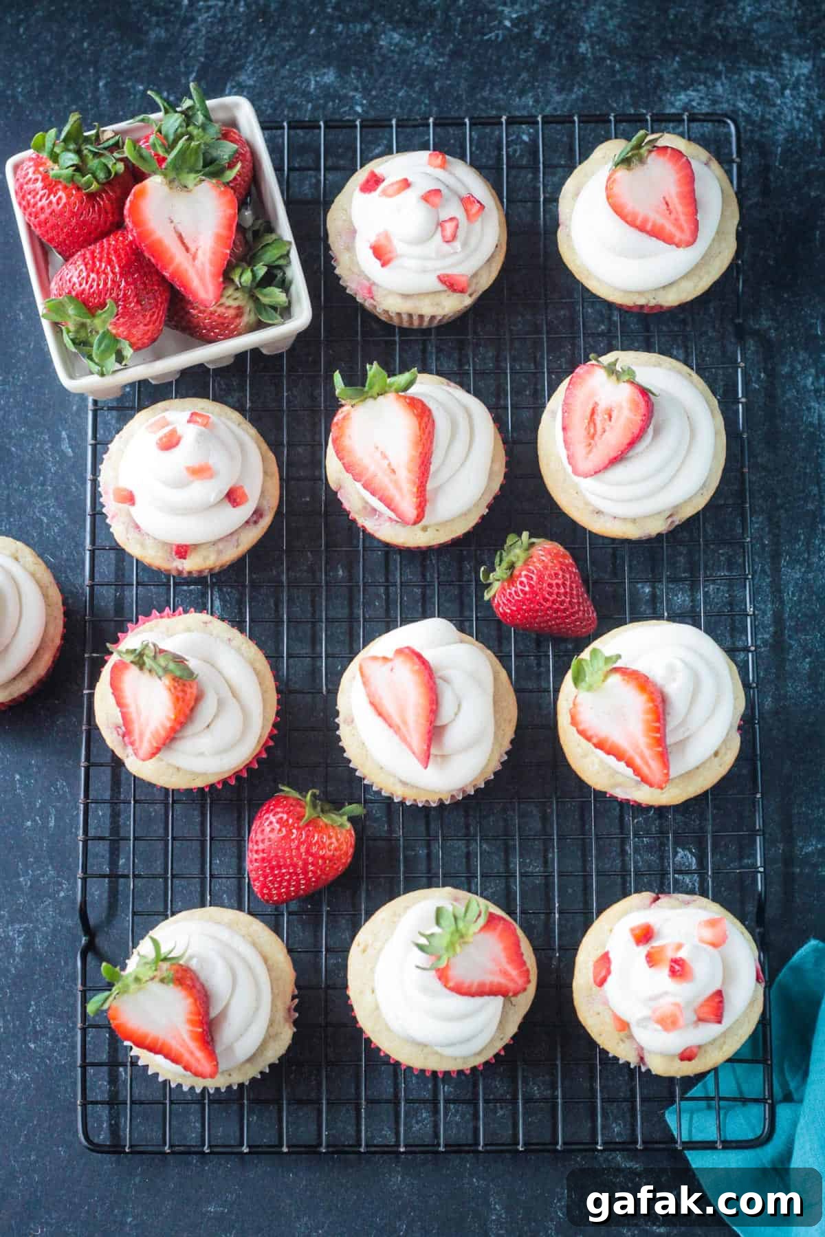 Frosted cupcakes topped with a halved fresh strawberry.