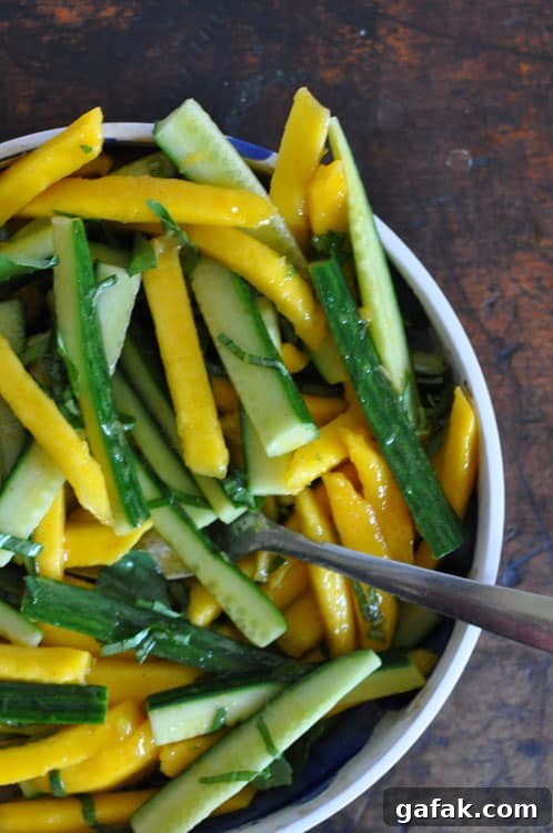 Mango and Cucumber Salad with Spicy Cayenne Dressing 5 Mango-Cucmber Salad with Cayenne Dressing in a shallow bowl on a wooden table.