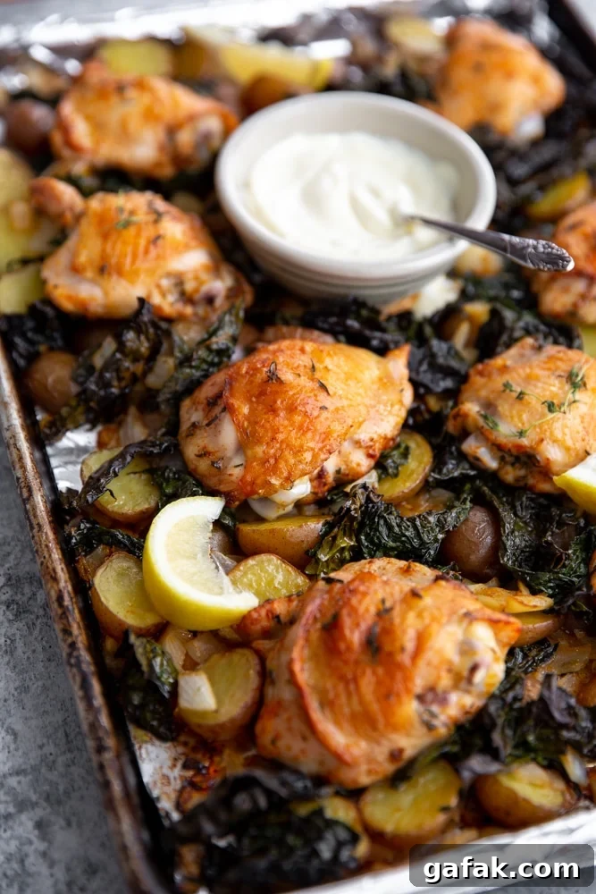 Close up of crispy sheet pan chicken and veggies with a bowl of aioli.