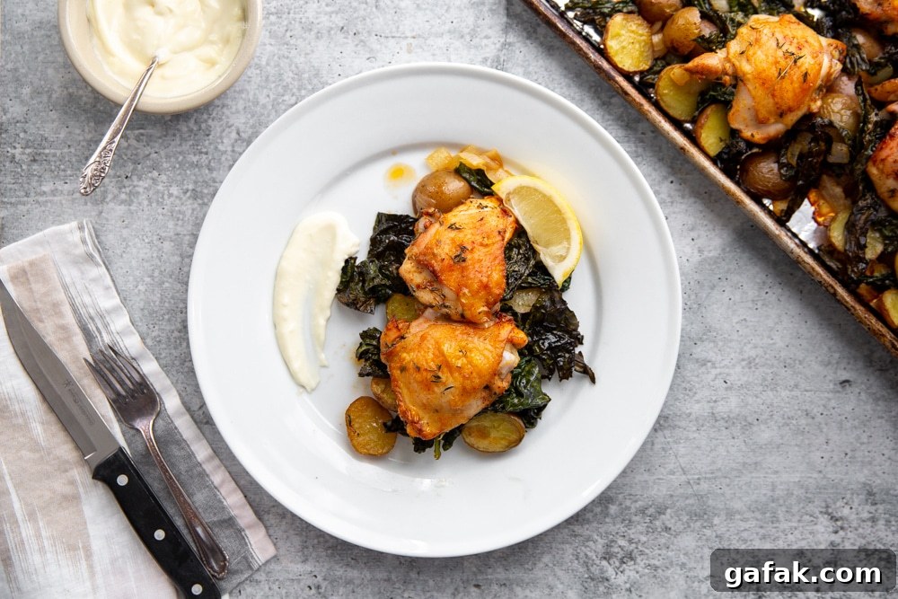 Sheet pan chicken and veggies on a plate with garlic aioli alongside.