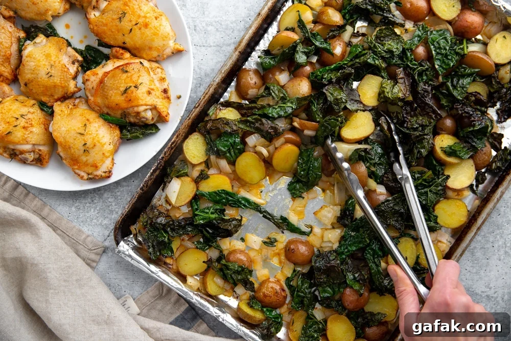 Process shot showing tongs stirring the sheet pan veggies halfway through the cooking time, with the chicken thighs on a plate alongside.