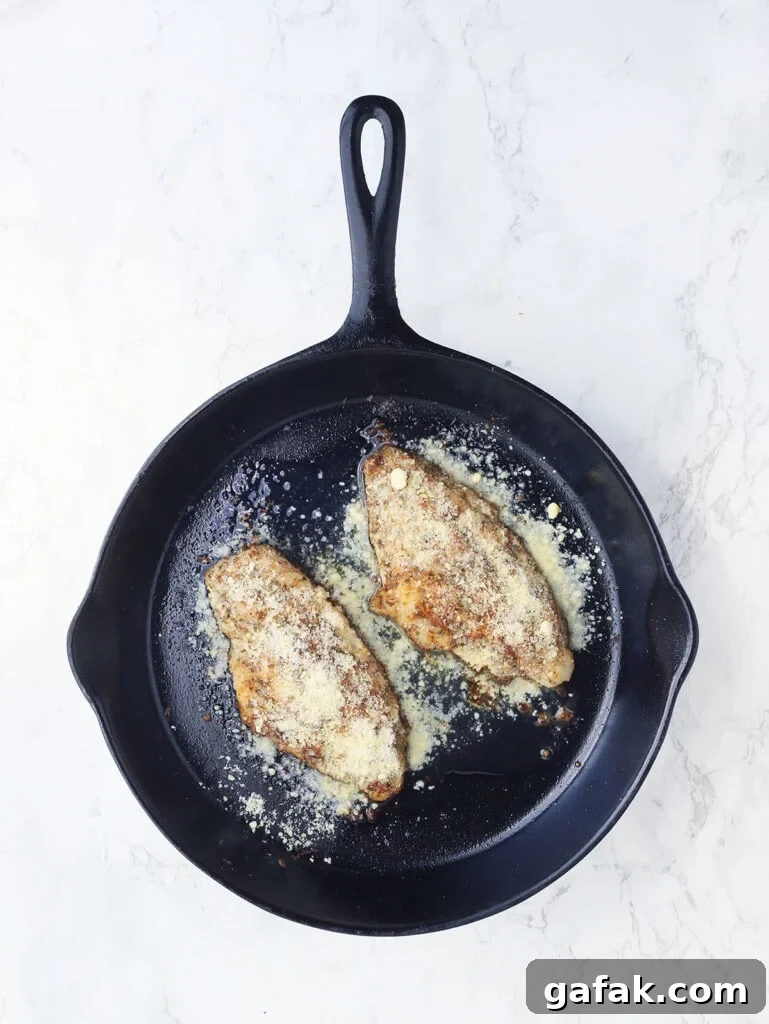 Catfish fillets after being topped with grated Parmesan cheese.