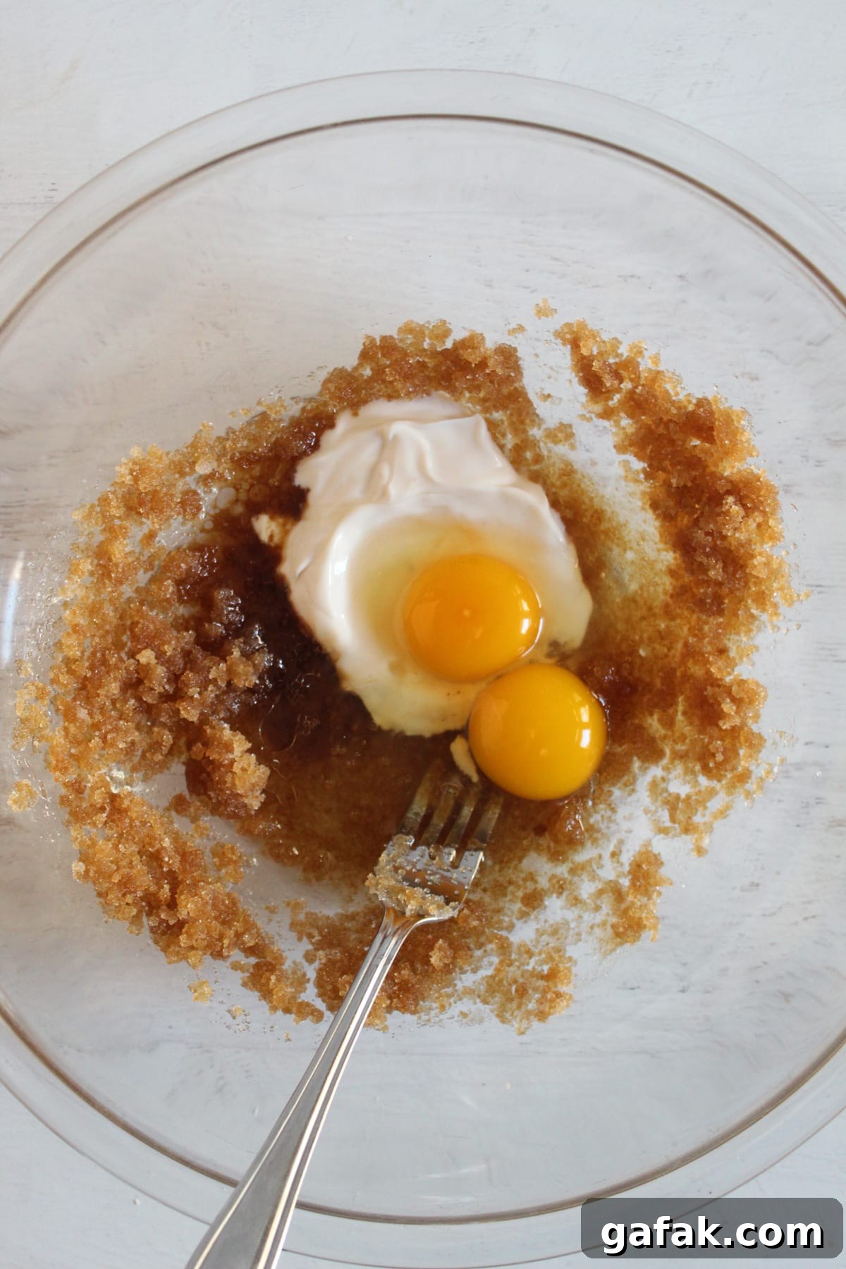 adding eggs to large glass bowl.