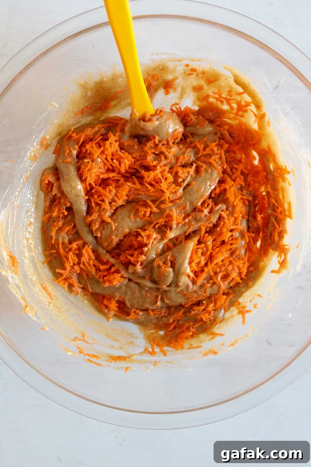 adding shredded carrots to the carrot cake donut batter