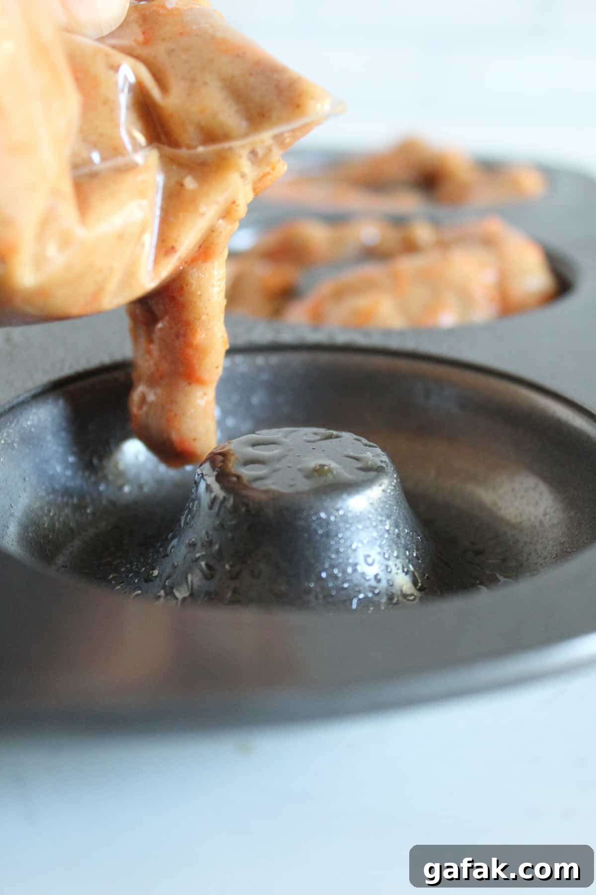 portioning donut batter into a donut pan.