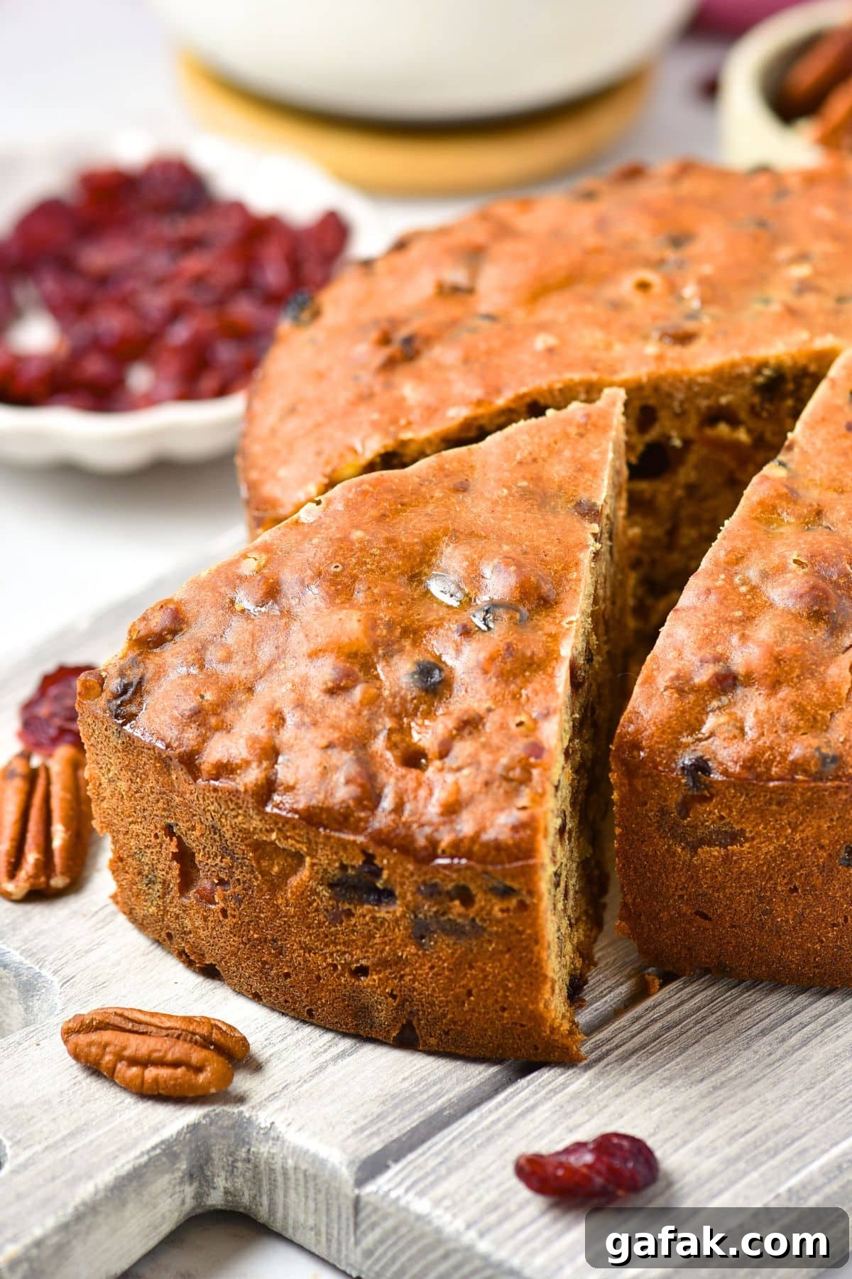 Easy Gluten-Free Fruit Cake (Dairy-Free) A half-sliced gluten-free fruit cake on wooden board.
