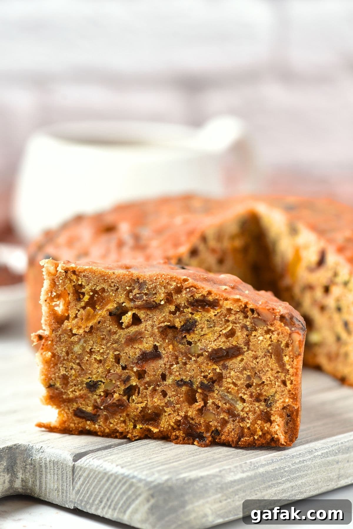 Gluten Free Fruit and Nut Cake Up close view of texture of a slice of fruit and nut cake on wooden board.