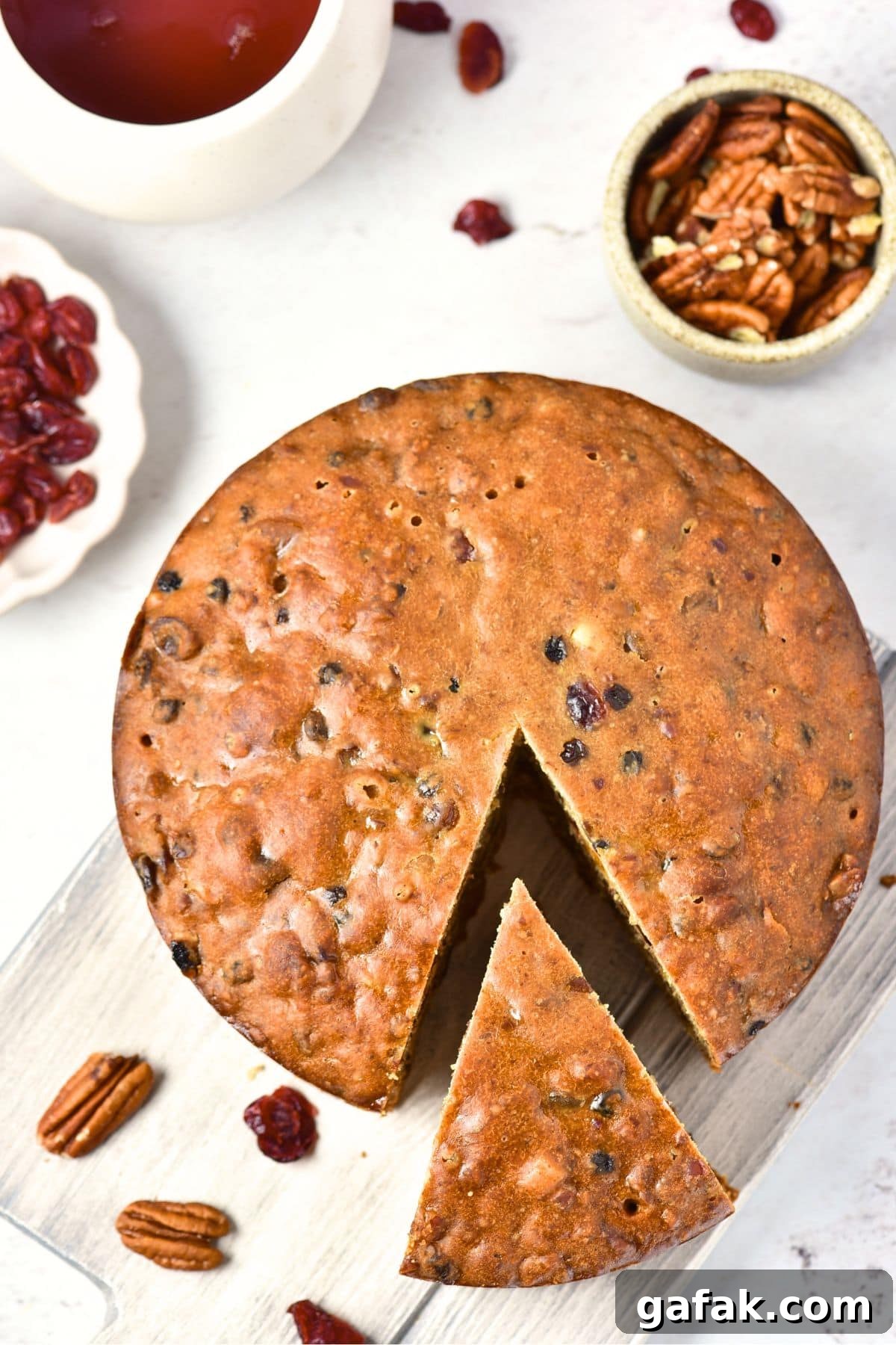 Easy Gluten-Free Fruit and Nut Cake Top down view of half-sliced fruit and nut cake on wooden board.