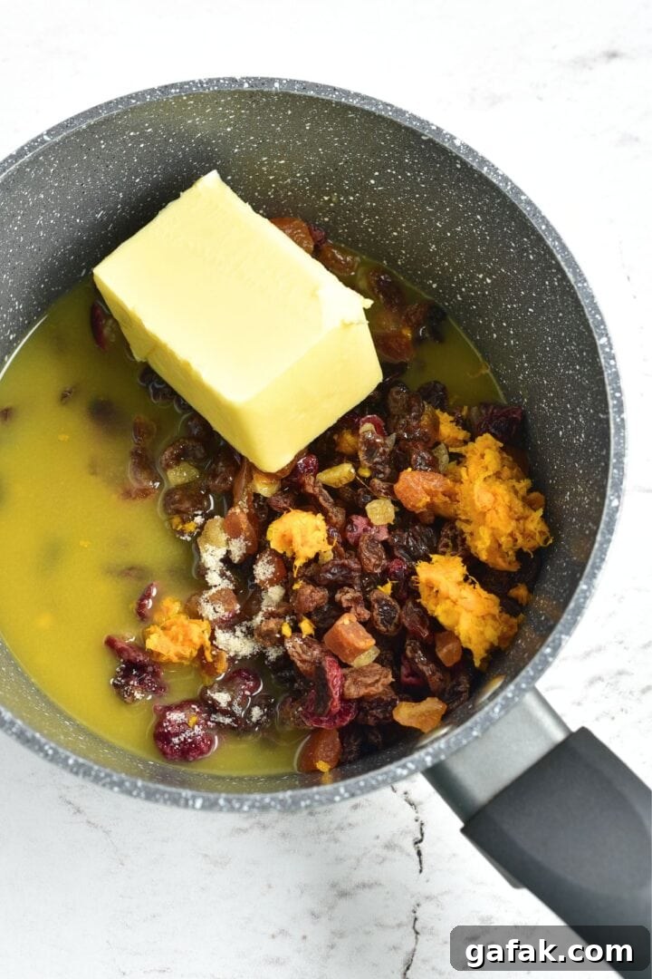 Gluten-Free Fruitcake Recipe A saucepan with butter, orange juice, dried fruits.