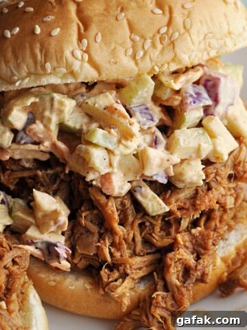 Pulled pork sandwich with apple slaw on sesame seed bun