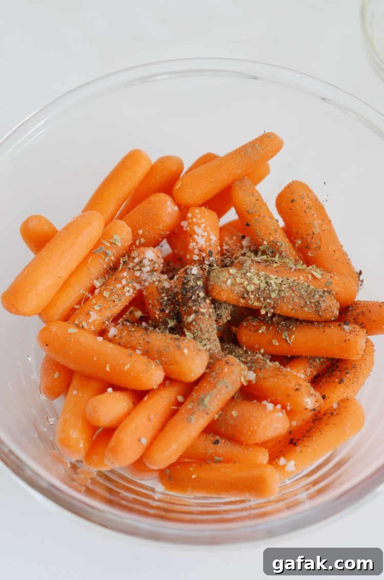Crispy Air Fryer Baby Carrots Recipe for Quick Side Dish 5 Baby Carrots in a bowl with dried herbs, salt, pepper and olive oil.