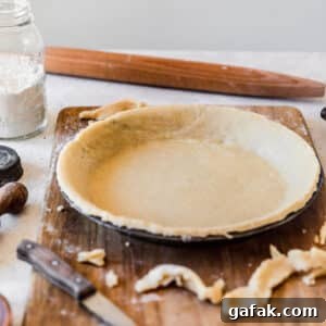 The best pie crust in a metal pan on a wood board with a white background.