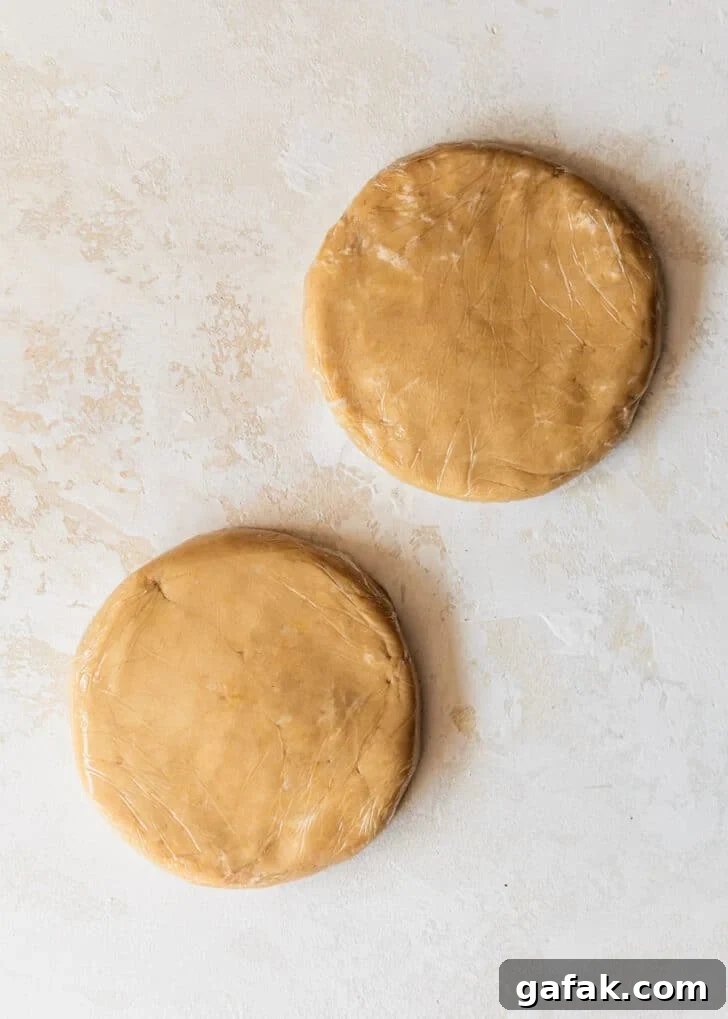 Two discs of the best pie crust on a tan counter.