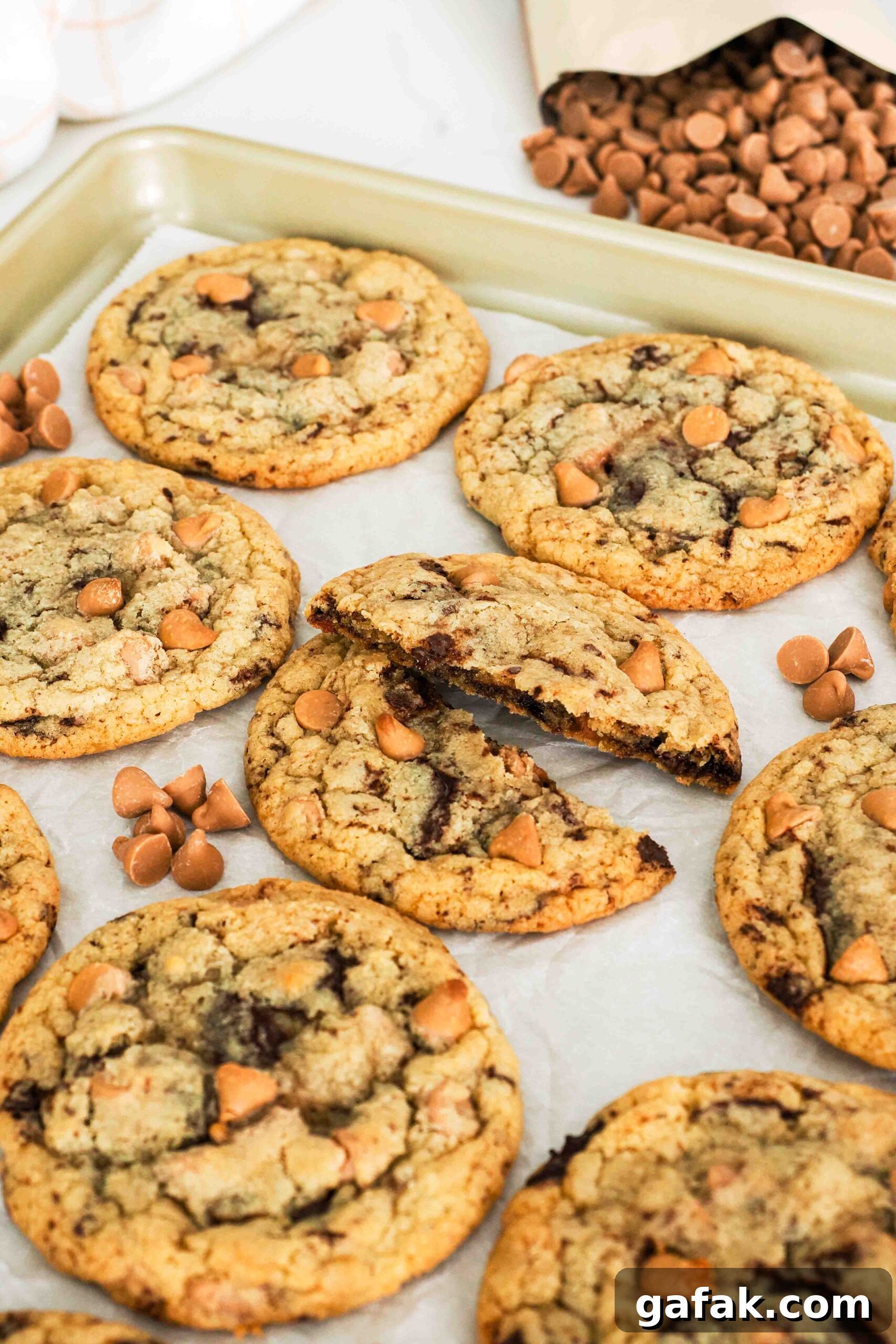 A caramel chocolate chip cookie is broken in half.