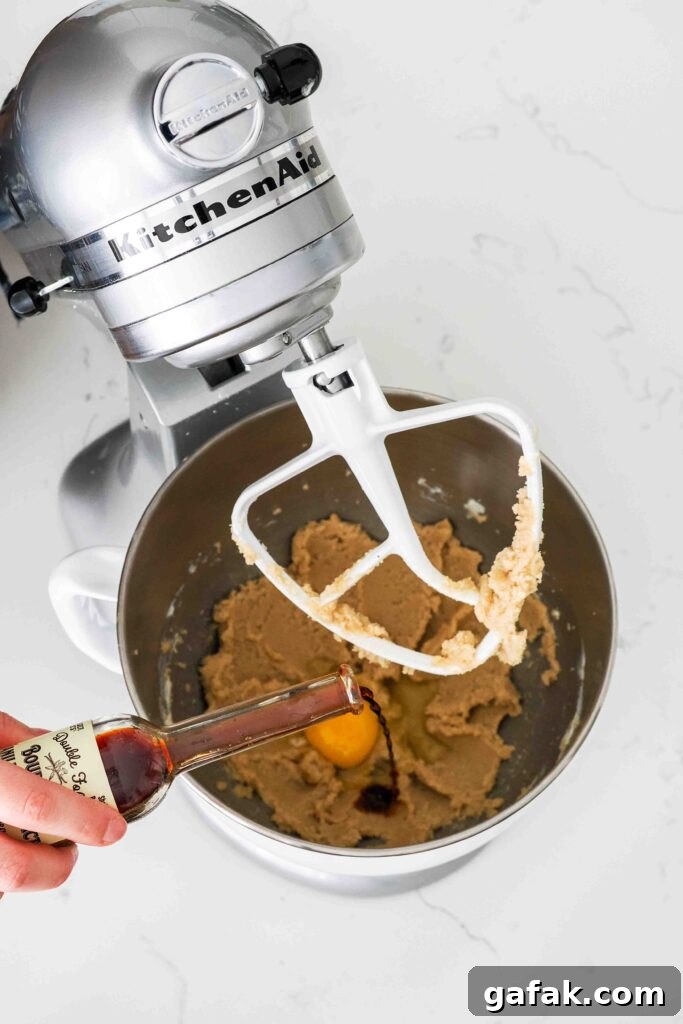 Vanilla is poured into a mixing bowl with creamed butter and sugar.