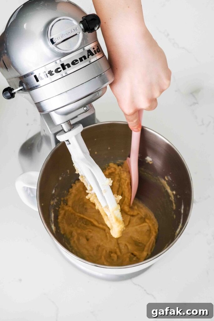 A spatula scrapes down the sides of a mixer bowl.