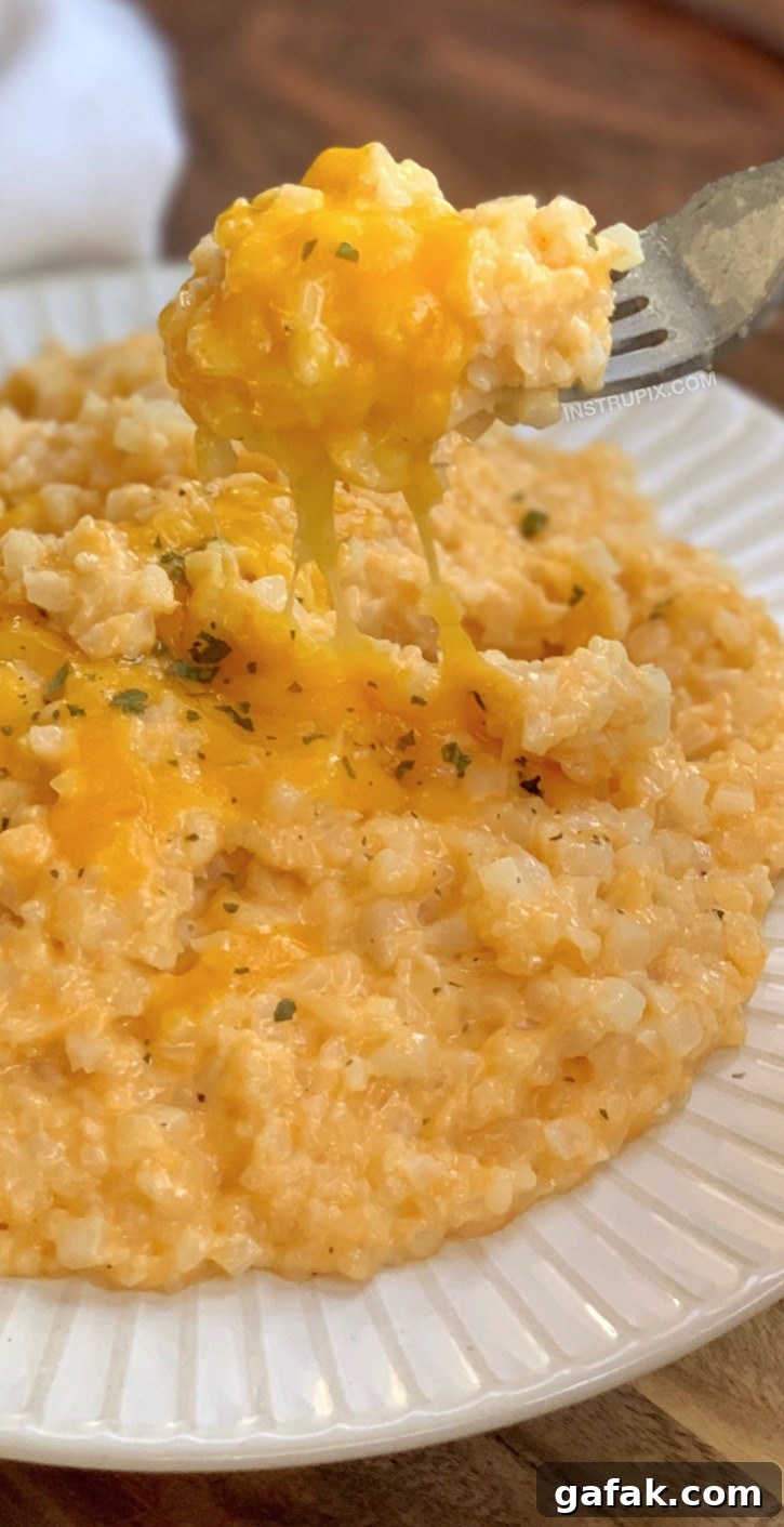 Quick and easy keto side dish recipe: Low Carb Cheesy Cauliflower Rice made with cheddar, butter, cream cheese, milk and garlic.
