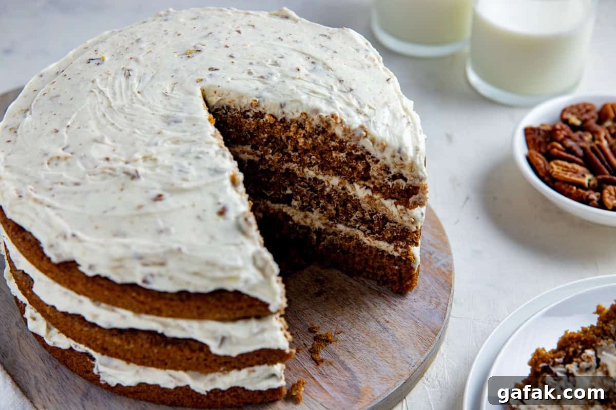 Baked and frosted 3-layer carrot cake with one serving removed on round wooden cake platter.