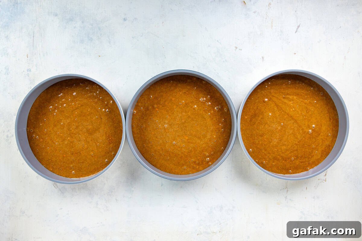 Cake batter in three round cake pans.