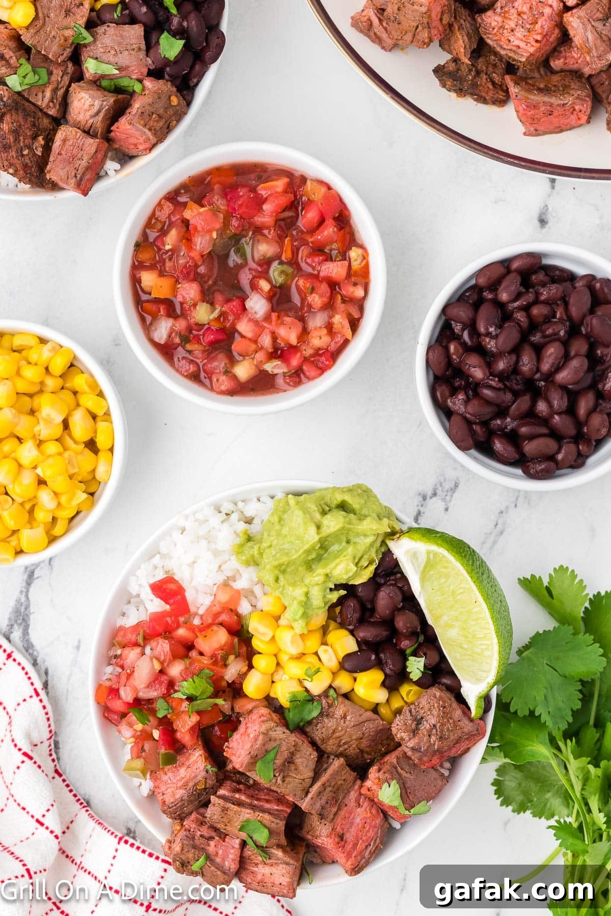Chipotle Steak Recipe: Smoky Grilled Steak with Chili-Lime Rub 10 Diced steak in a bowl with white rice, guacamole, diced tomatoes, corn, black beans with lime wedges