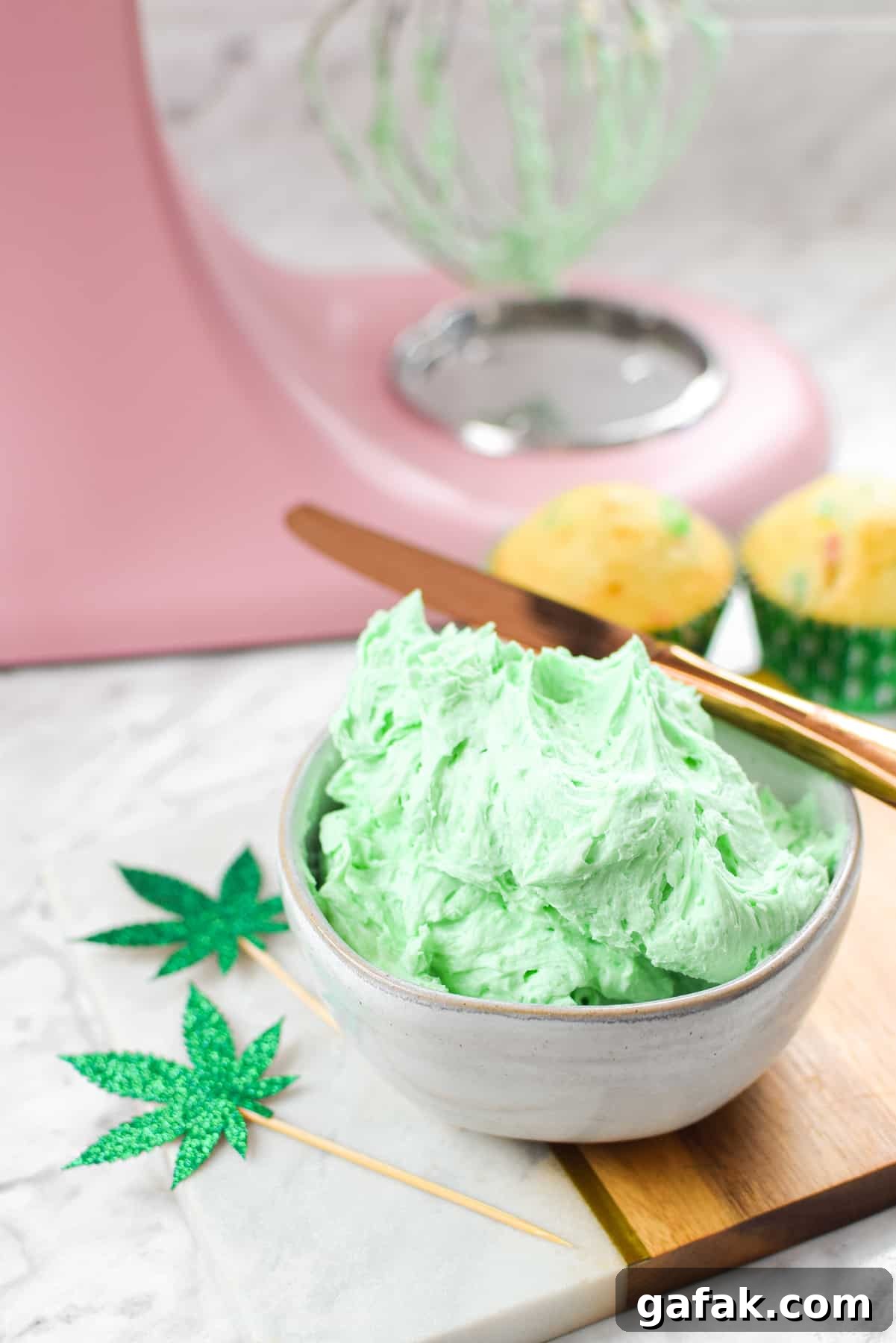 A white countertop with a bowl of green cannabis buttercream frosting