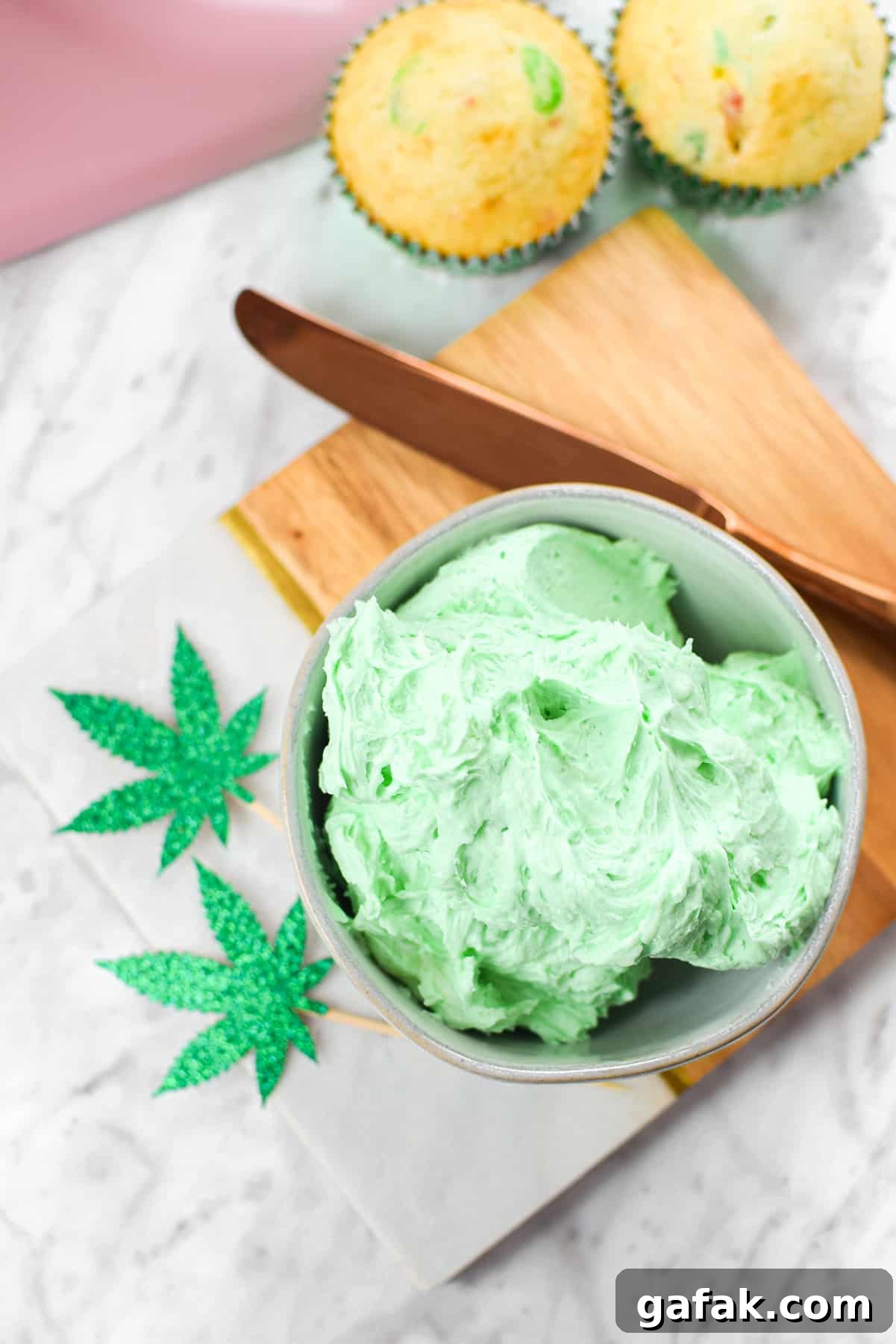 A white countertop with a bowl of green cannabis buttercream frosting