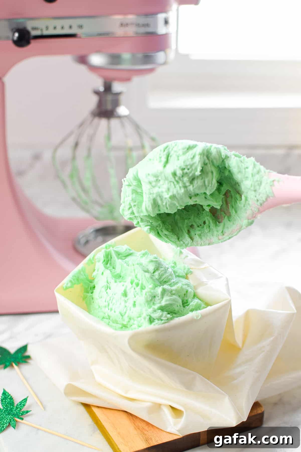 A white countertop with a bowl of green cannabis buttercream frosting